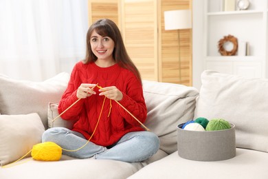 Photo of Beautiful woman knitting on sofa at home