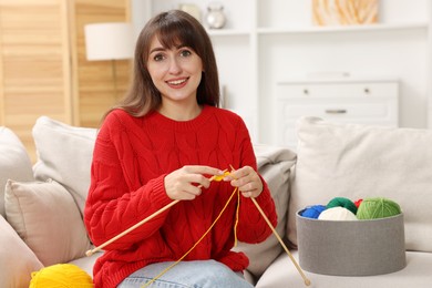 Photo of Beautiful woman knitting on sofa at home