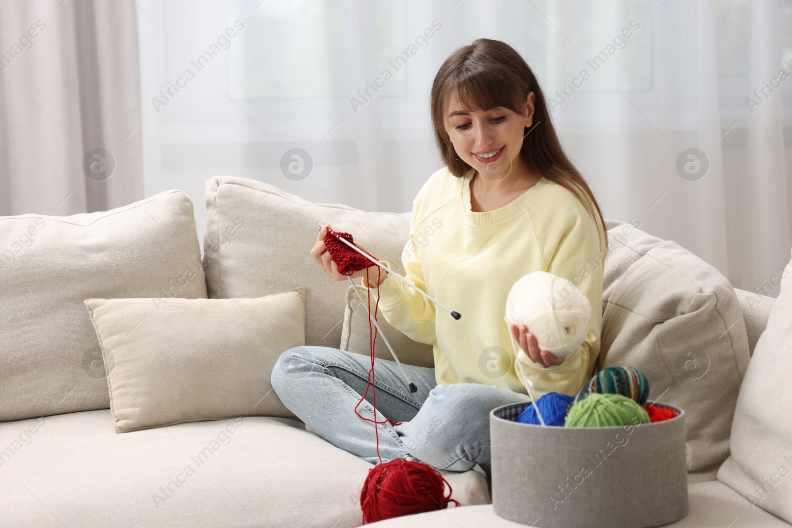 Photo of Beautiful woman knitting on sofa at home