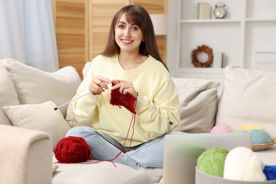 Beautiful woman learning to knit with online course at home