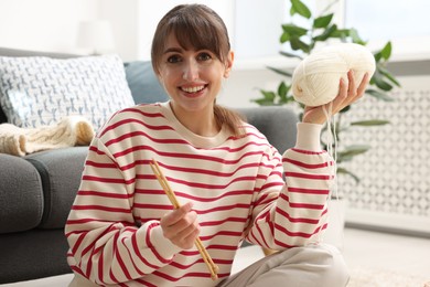 Beautiful woman with yarn and knitting needles at home