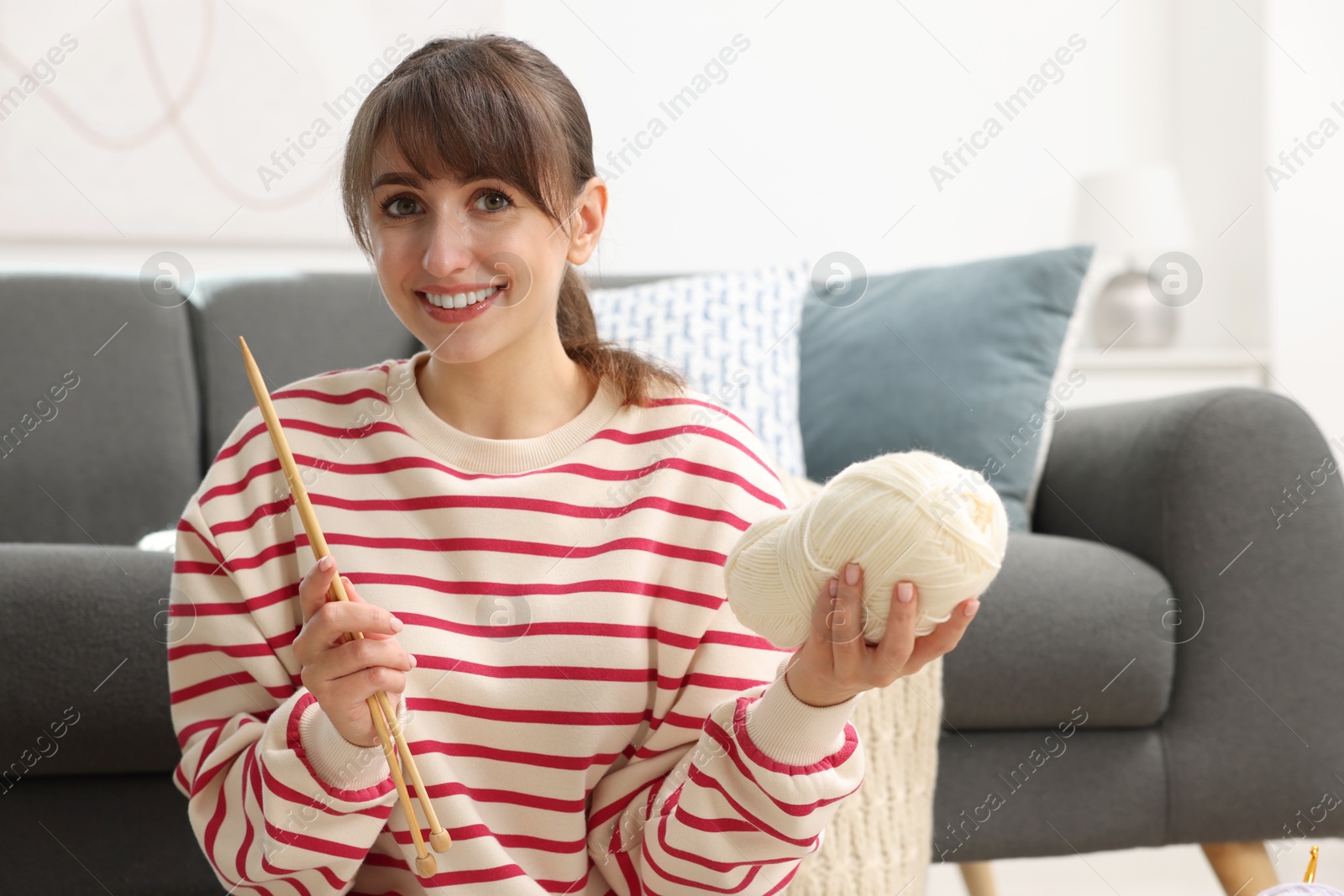 Photo of Beautiful woman with yarn and knitting needles at home