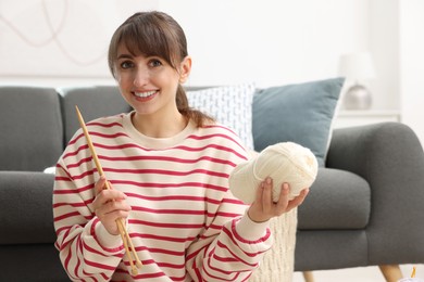 Photo of Beautiful woman with yarn and knitting needles at home