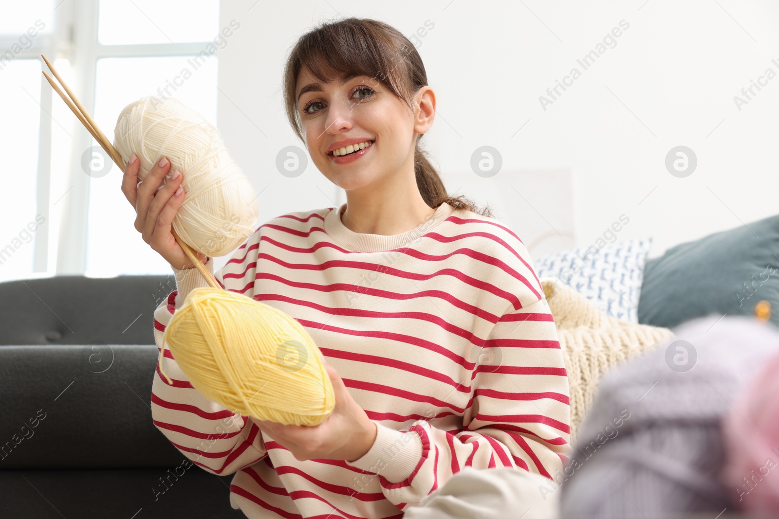 Photo of Beautiful woman with colorful yarns and knitting needles at home