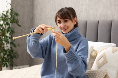 Photo of Beautiful woman knitting with needles on bed at home