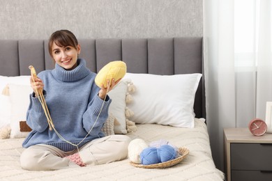 Beautiful woman knitting with needles on bed at home