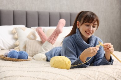 Photo of Beautiful woman knitting with needles on bed at home