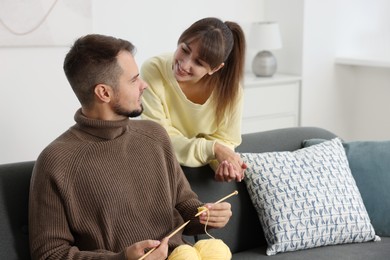 Woman teaching her boyfriend how to knit at home