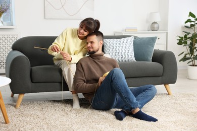 Photo of Woman teaching her boyfriend how to knit at home