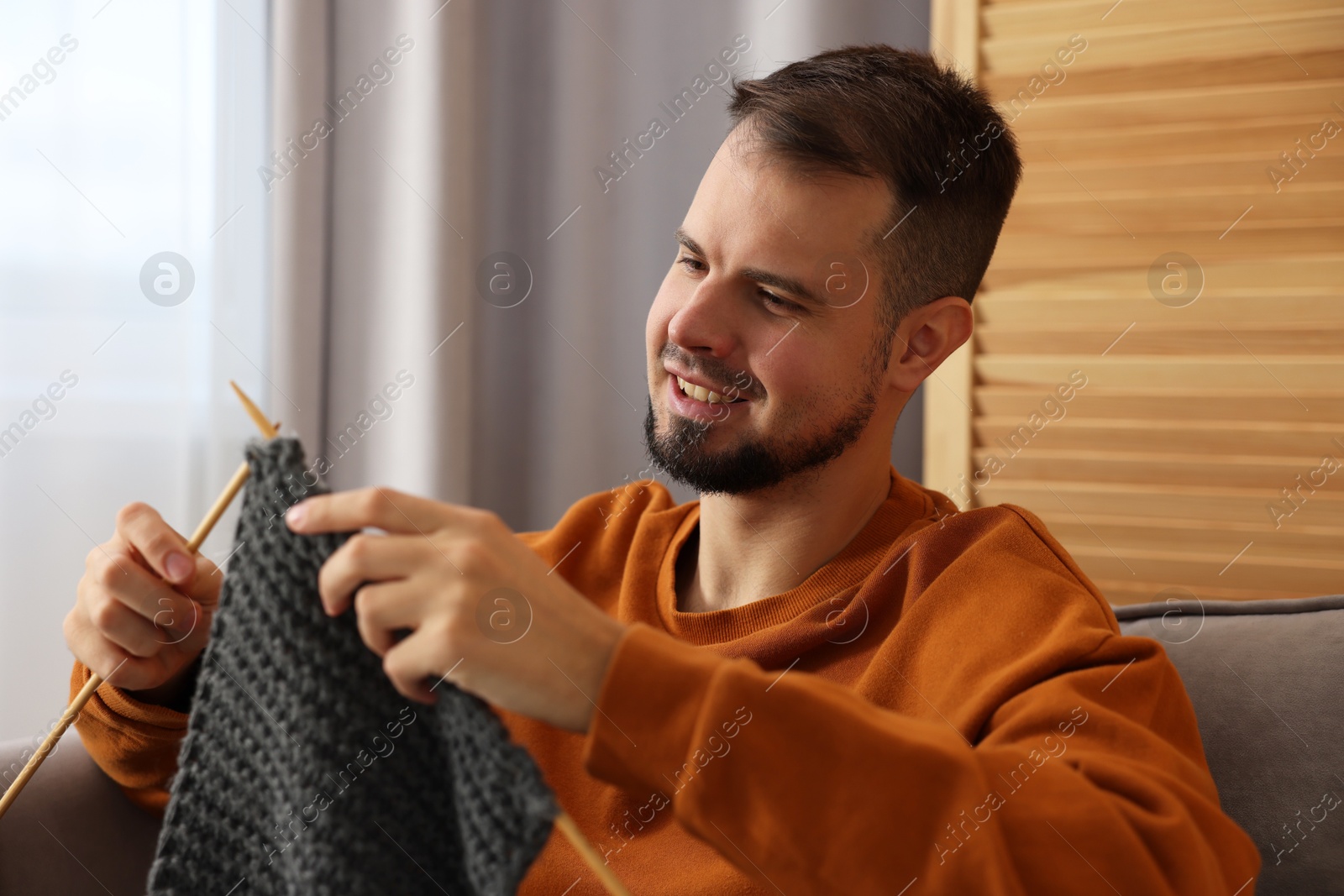 Photo of Man knitting with needles in armchair at home