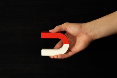 Photo of Man holding horseshoe magnet on dark background, closeup