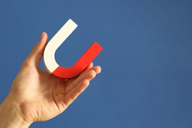 Photo of Man holding horseshoe magnet on blue background, closeup. Space for text