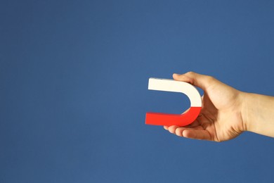 Photo of Man holding horseshoe magnet on blue background, closeup. Space for text