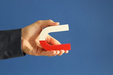 Photo of Man holding horseshoe magnet on blue background, closeup. Space for text