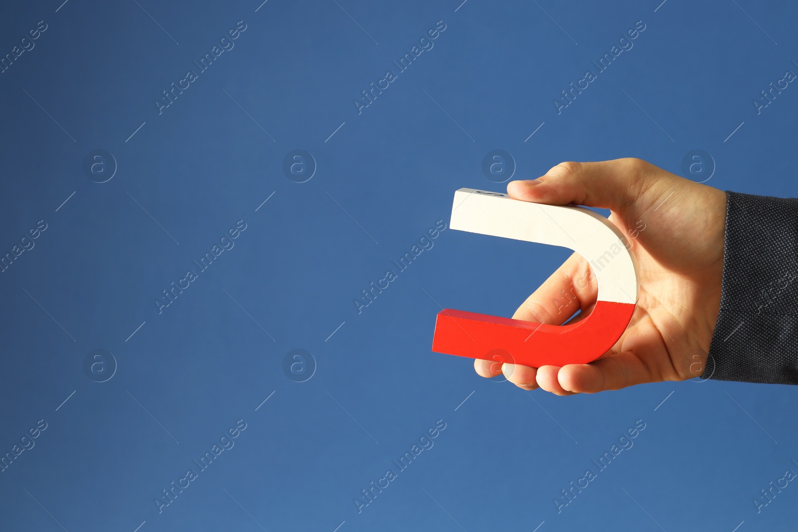 Photo of Man holding horseshoe magnet on blue background, closeup. Space for text