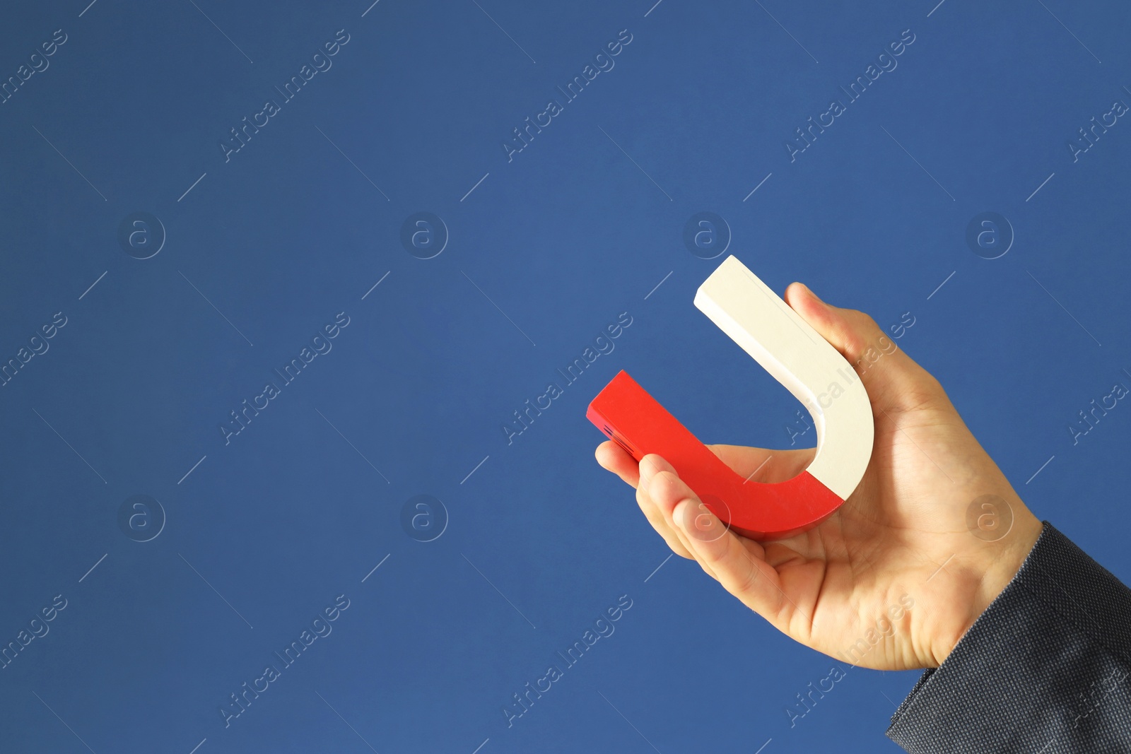 Photo of Man holding horseshoe magnet on blue background, closeup. Space for text