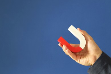 Photo of Man holding horseshoe magnet on blue background, closeup. Space for text