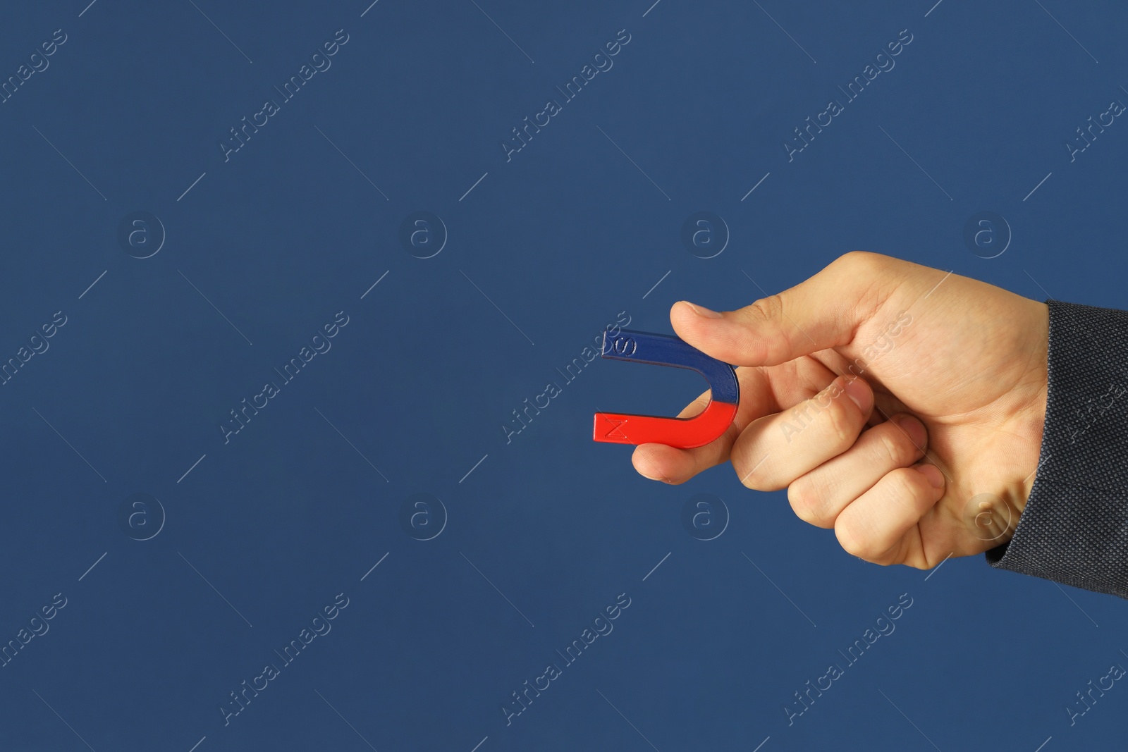 Photo of Man holding horseshoe magnet on blue background, closeup. Space for text