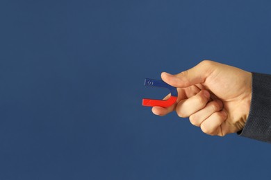 Photo of Man holding horseshoe magnet on blue background, closeup. Space for text