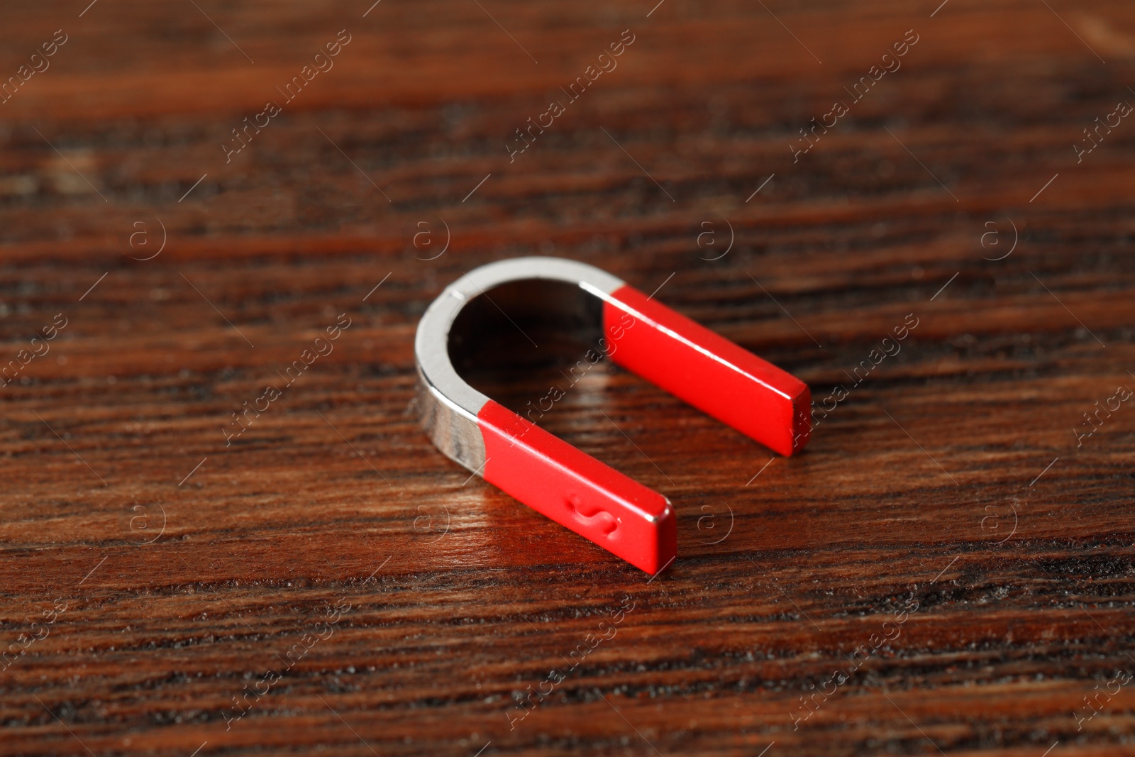 Photo of One horseshoe magnet on wooden table, closeup