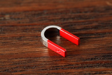 Photo of One horseshoe magnet on wooden table, closeup