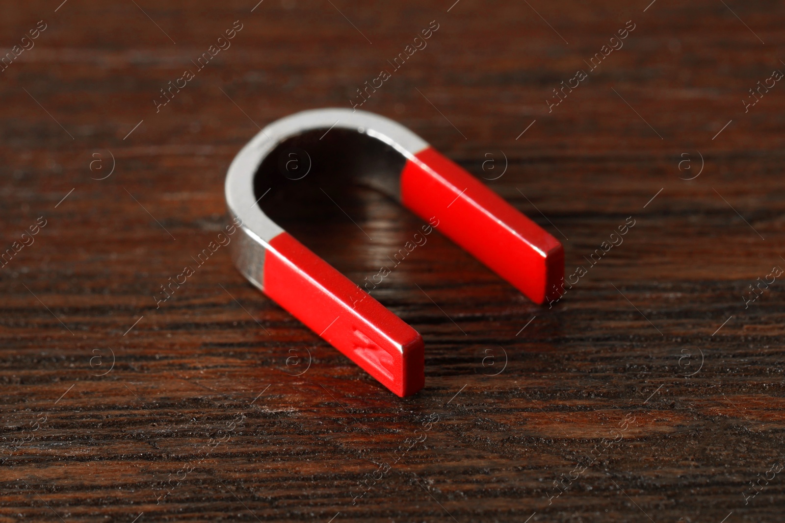 Photo of One horseshoe magnet on wooden table, closeup