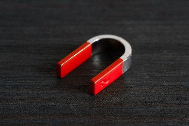 Photo of One horseshoe magnet on black wooden table, closeup