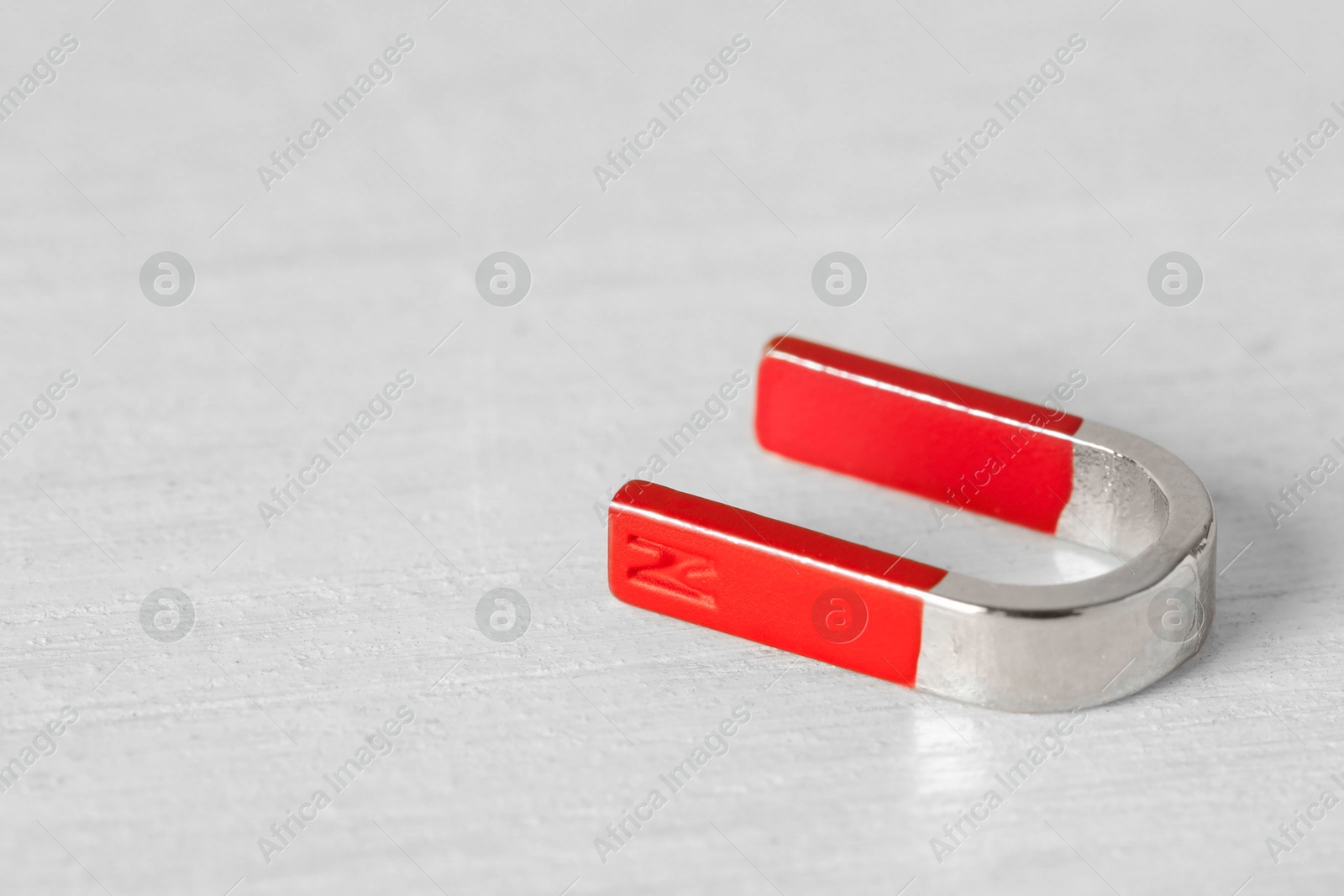 Photo of One horseshoe magnet on white wooden table, closeup. Space for text