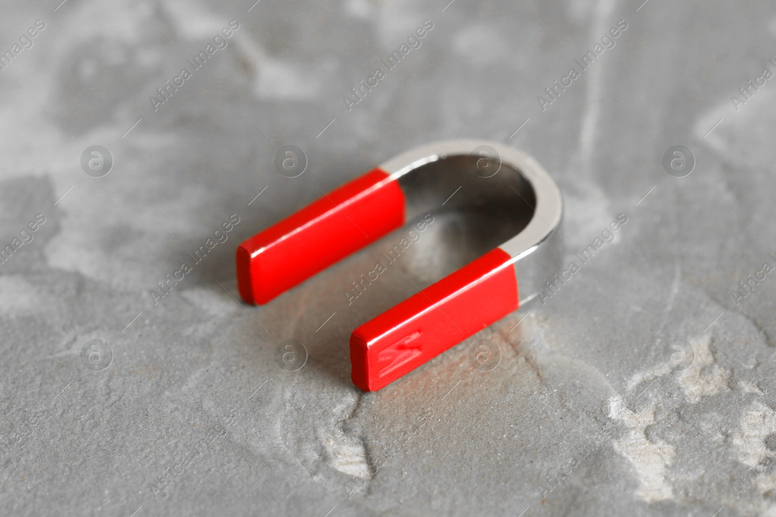 Photo of One horseshoe magnet on grey textured table, closeup