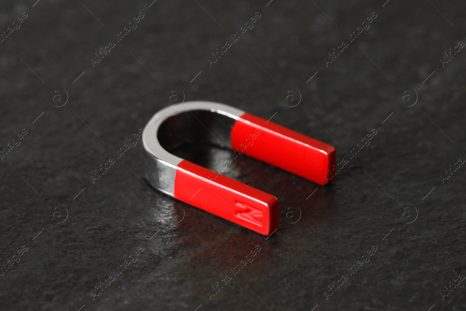 Photo of One horseshoe magnet on dark textured table, closeup