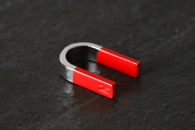 Photo of One horseshoe magnet on dark textured table, closeup