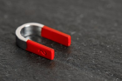 Photo of One horseshoe magnet on dark textured table, closeup. Space for text