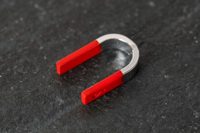 Photo of One horseshoe magnet on dark textured table, closeup