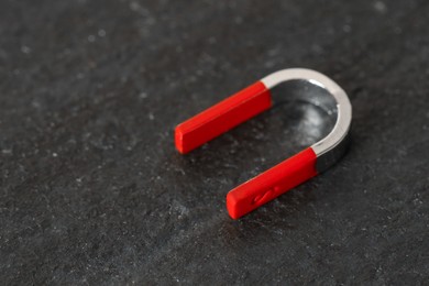 Photo of One horseshoe magnet on dark textured table, closeup