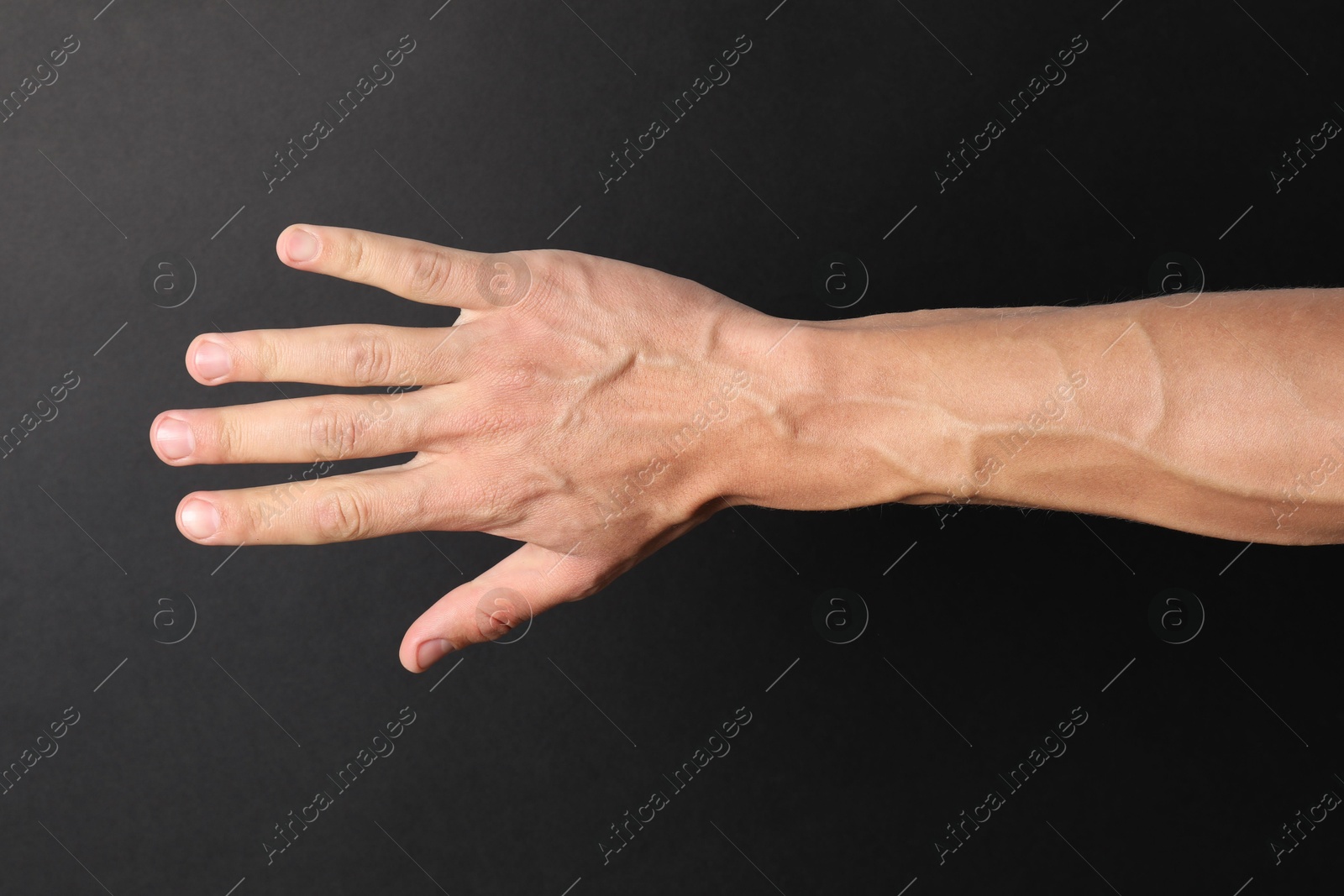 Photo of Man with bulging veins on his arm against black background, closeup