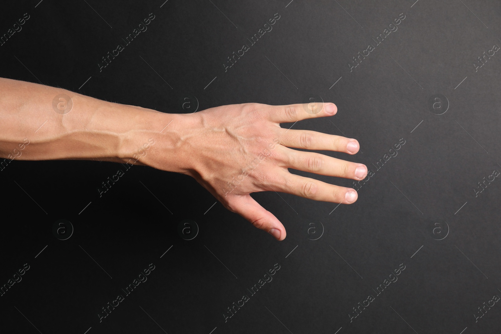 Photo of Man with bulging veins on his arm against black background, closeup