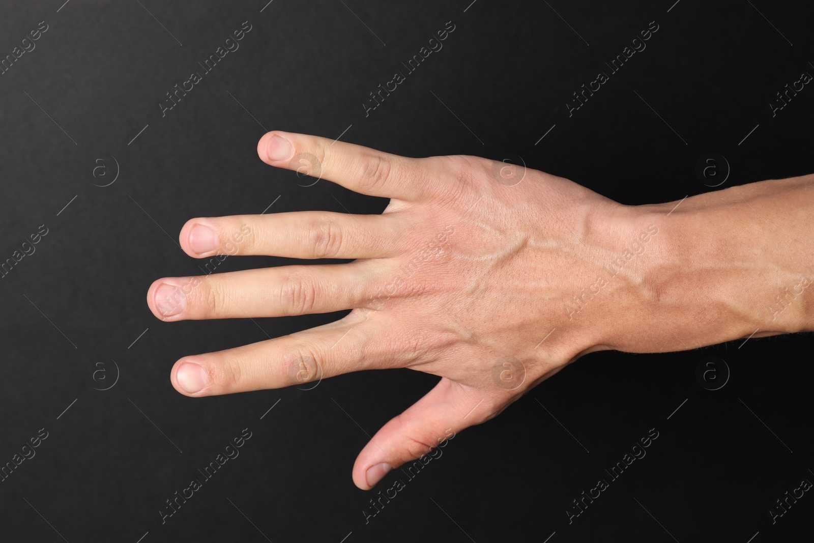 Photo of Man with bulging veins on his arm against black background, closeup