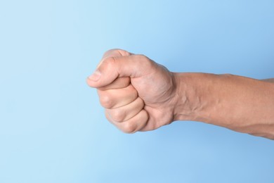 Photo of Man with bulging veins on his arm against light blue background, closeup