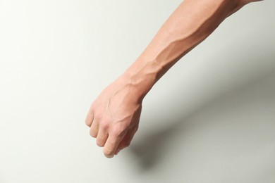 Photo of Man with bulging veins on his arm against light background, closeup