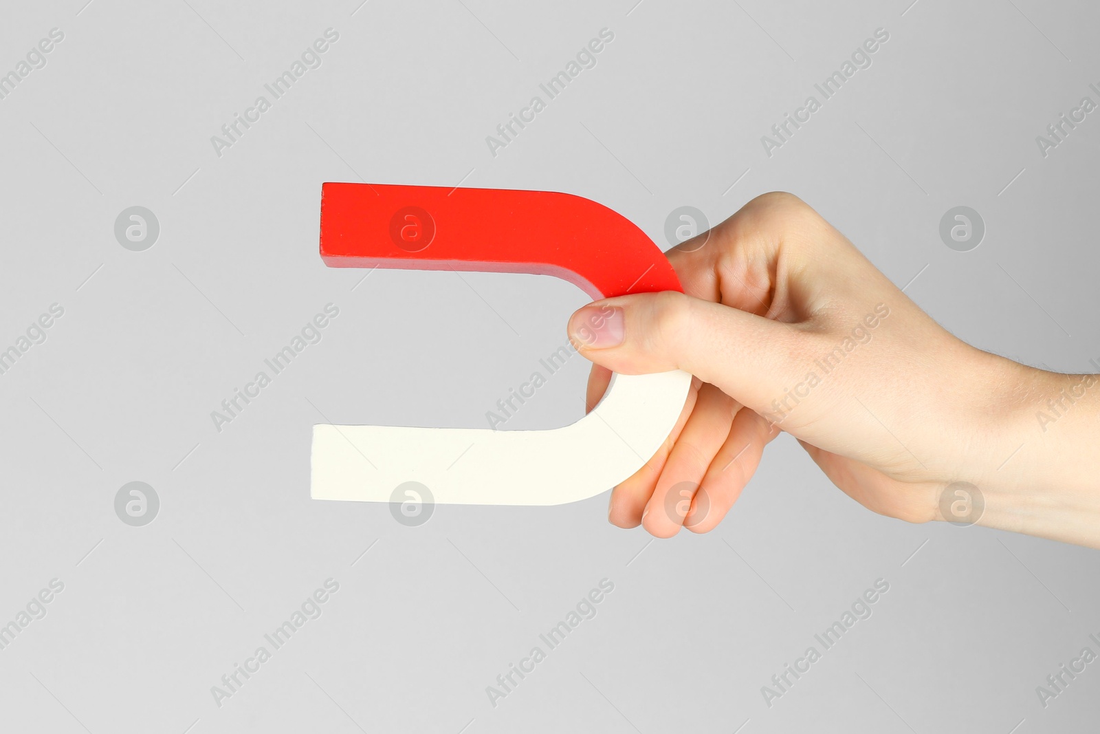 Photo of Woman with horseshoe magnet on grey background, closeup