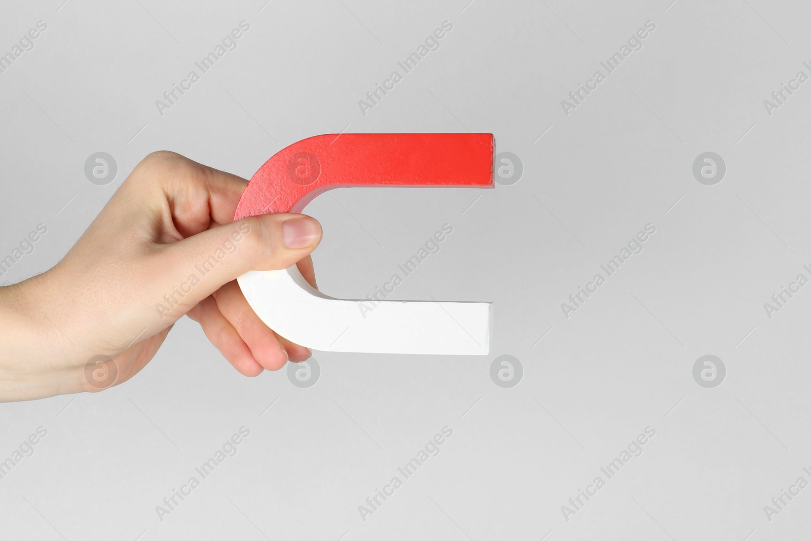 Photo of Woman with horseshoe magnet on grey background, closeup