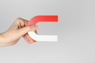 Photo of Woman with horseshoe magnet on grey background, closeup