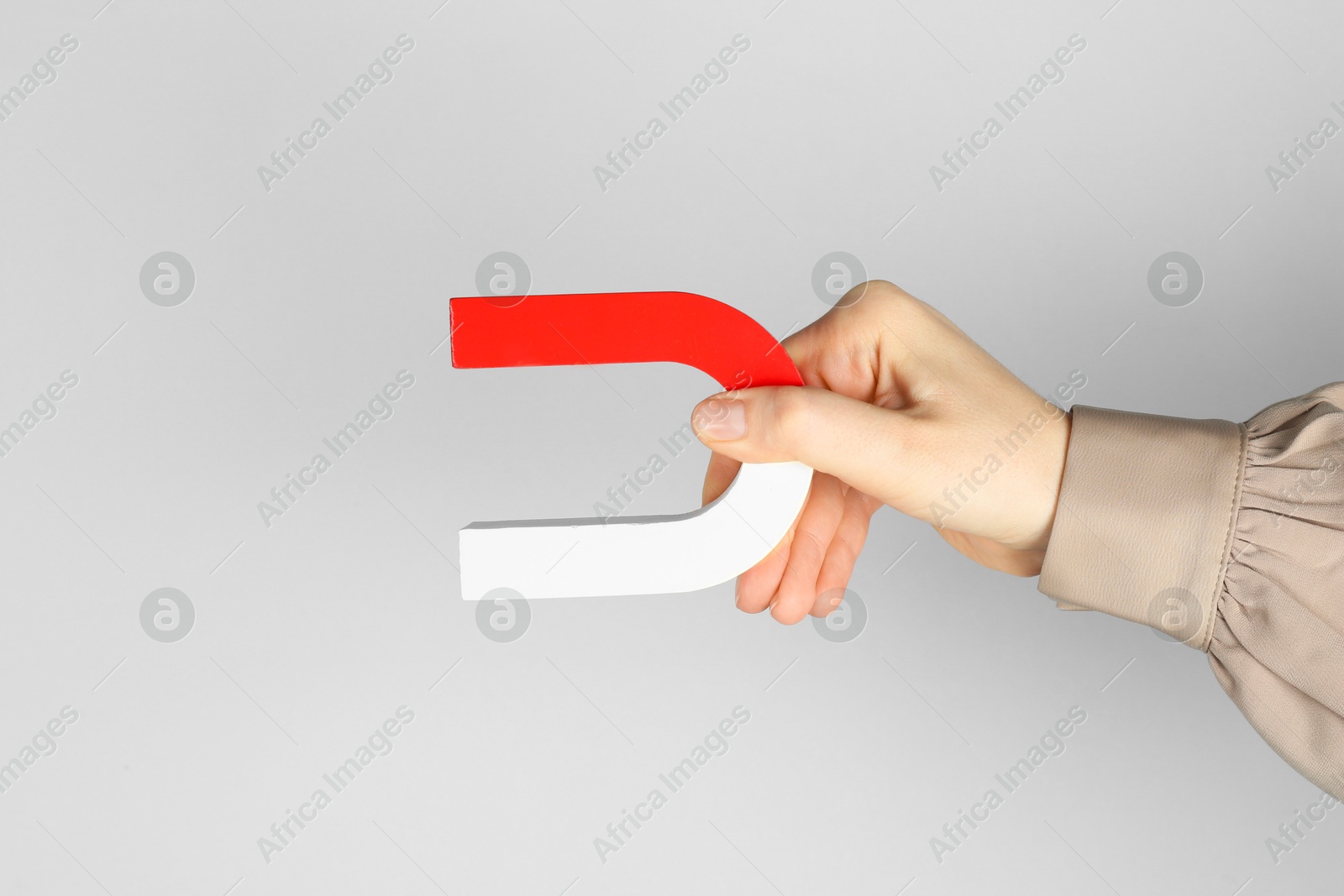 Photo of Woman with horseshoe magnet on grey background, closeup