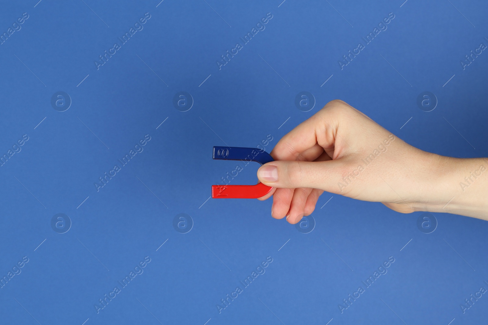 Photo of Woman with horseshoe magnet on blue background, closeup. Space for text