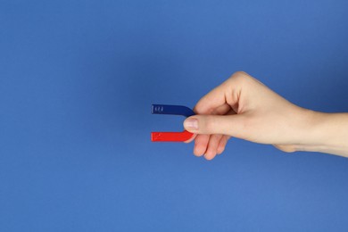 Photo of Woman with horseshoe magnet on blue background, closeup. Space for text