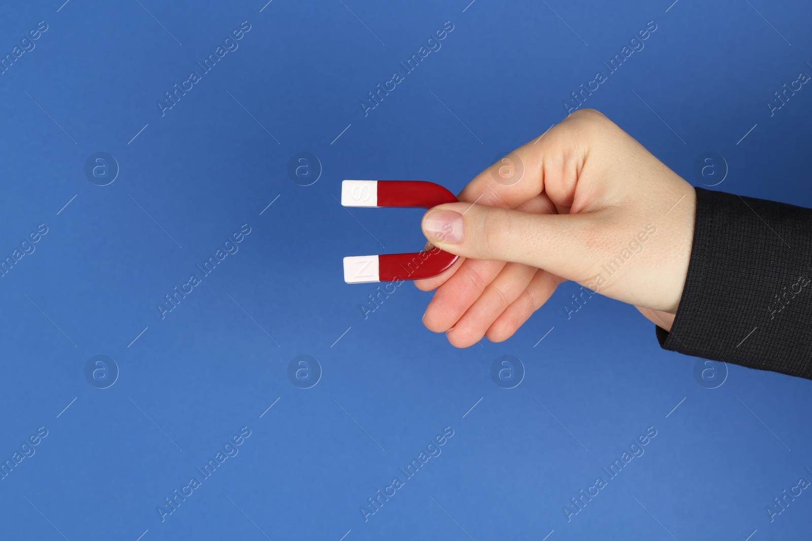 Photo of Woman with horseshoe magnet on blue background, closeup. Space for text