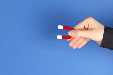 Photo of Woman with horseshoe magnet on blue background, closeup. Space for text