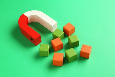 Photo of Magnet attracting colorful cubes on green background