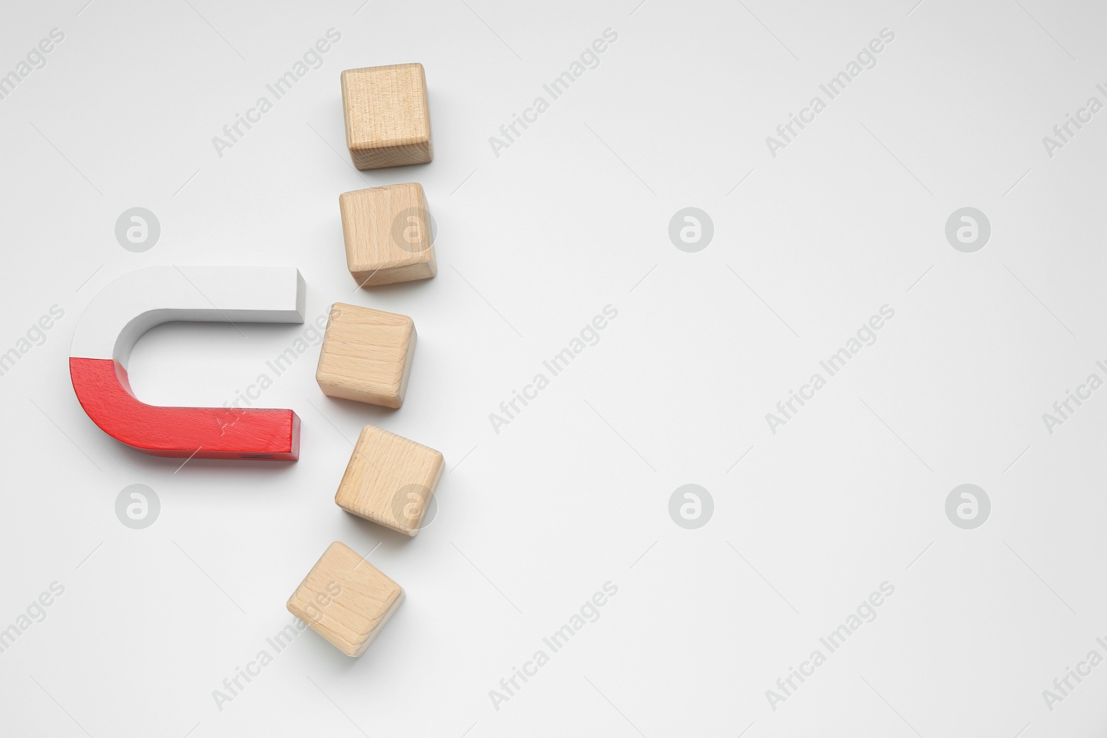 Photo of Magnet attracting wooden cubes on white background, flat lay. Space for text