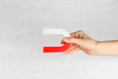 Photo of Woman with horseshoe magnet on light background, closeup